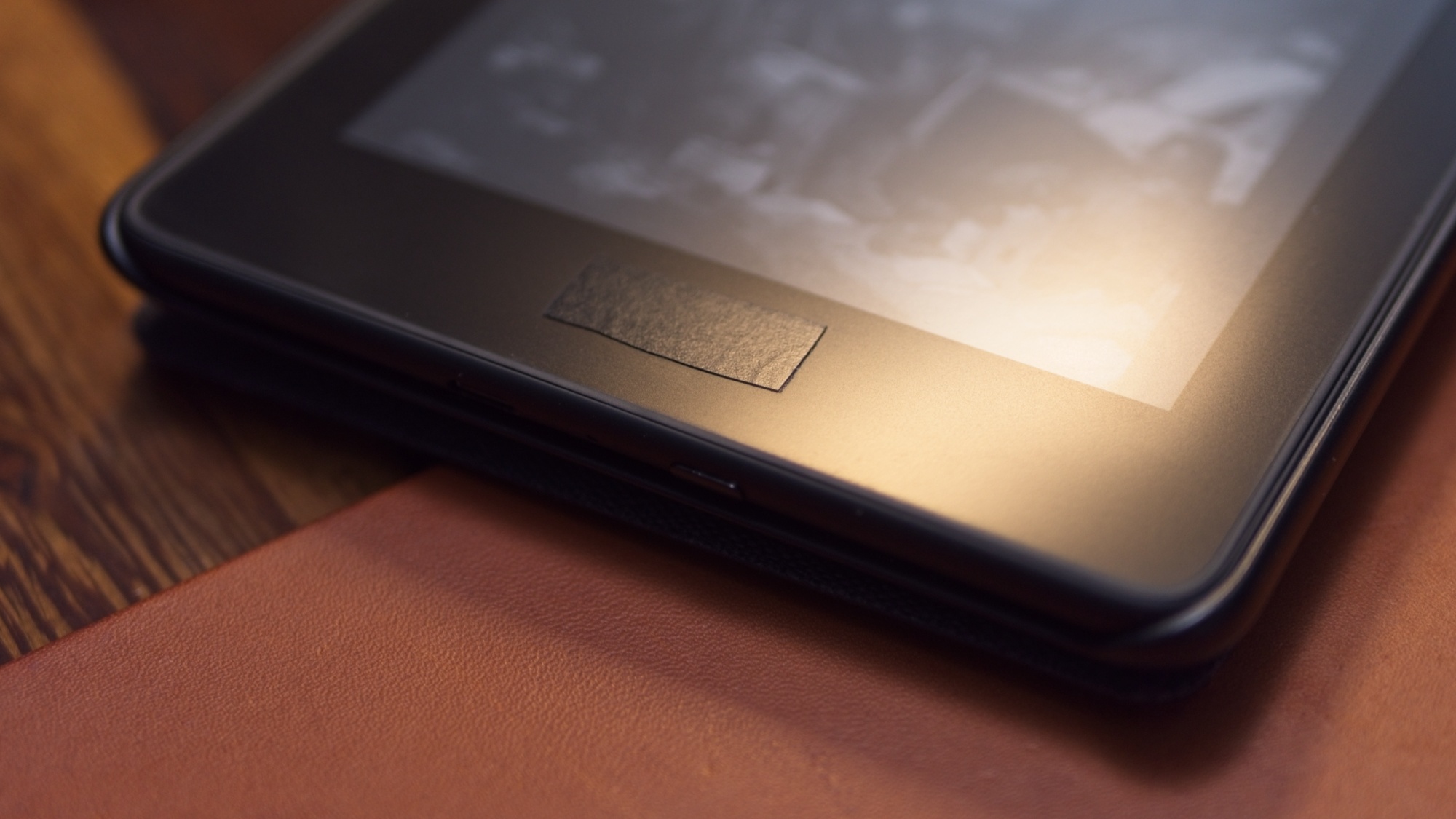 Tightly-cropped closeup photo of the author’s kindle, with crudely-cut black electrical tape where the word “kindle” would be on its face